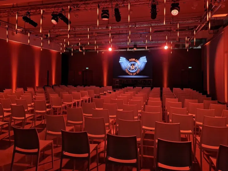 Sala con sedie rosse e luci rosse davanti al palco