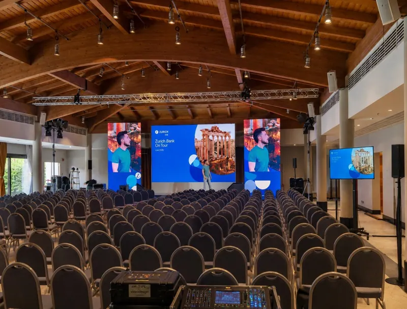 Sala congressi con palco, schermi LED centrali e laterali e luci blu