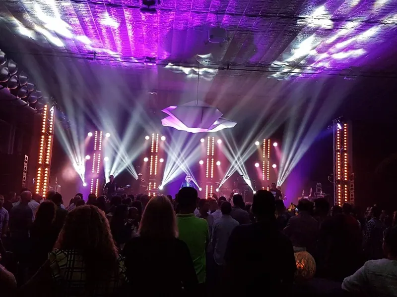 Palco con fasci di luce bianca e viola durante uno show