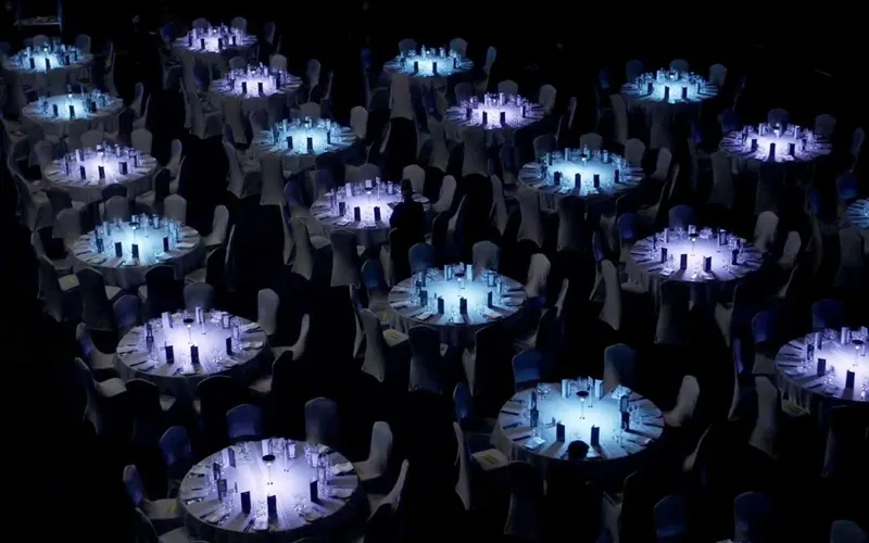 Tavoli da gala illuminati dall'alto nel buio della sala