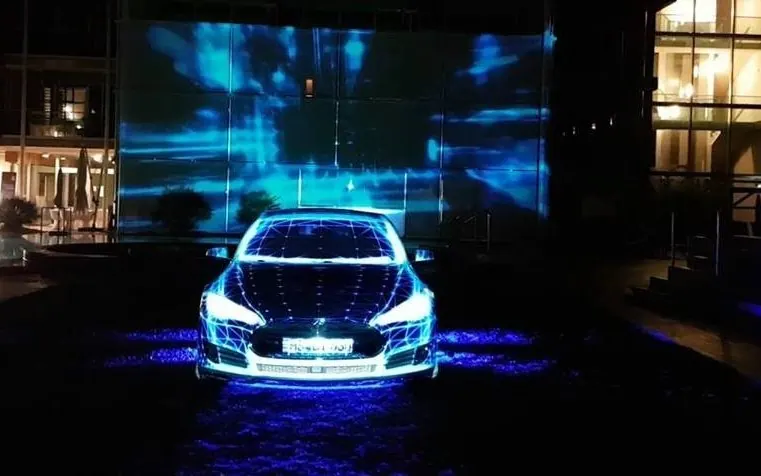 Auto illuminata da proiezioni azzurre durante una presentazione