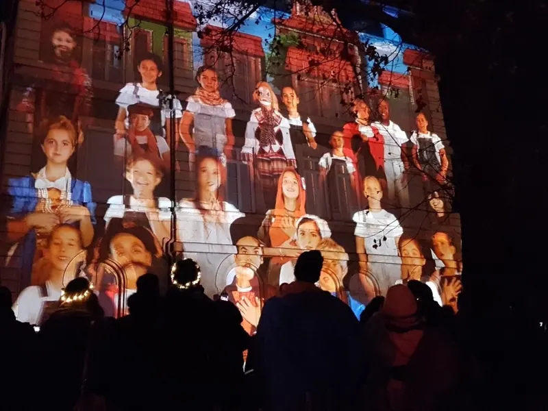 Videomapping con volti di bambini proiettati su una facciata